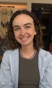 Marissa Perry looks into the camera and smiles. She is inside wearing a blue jacket.