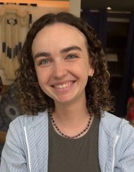 Marissa Perry looks into the camera and smiles. She is inside wearing a blue jacket.