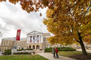 Pedestrians and students walk among the colors of the fall leaves near Bascom Hall.