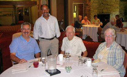 Faculty and board of visitors members gathering around a dining table.
