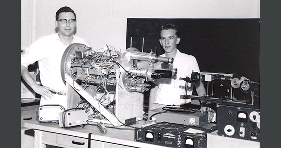 Black and white photo of two men gathering with an astronomy instrument.