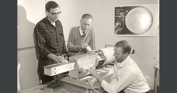 Historic photo of three men gathering among an astronomy instrument.