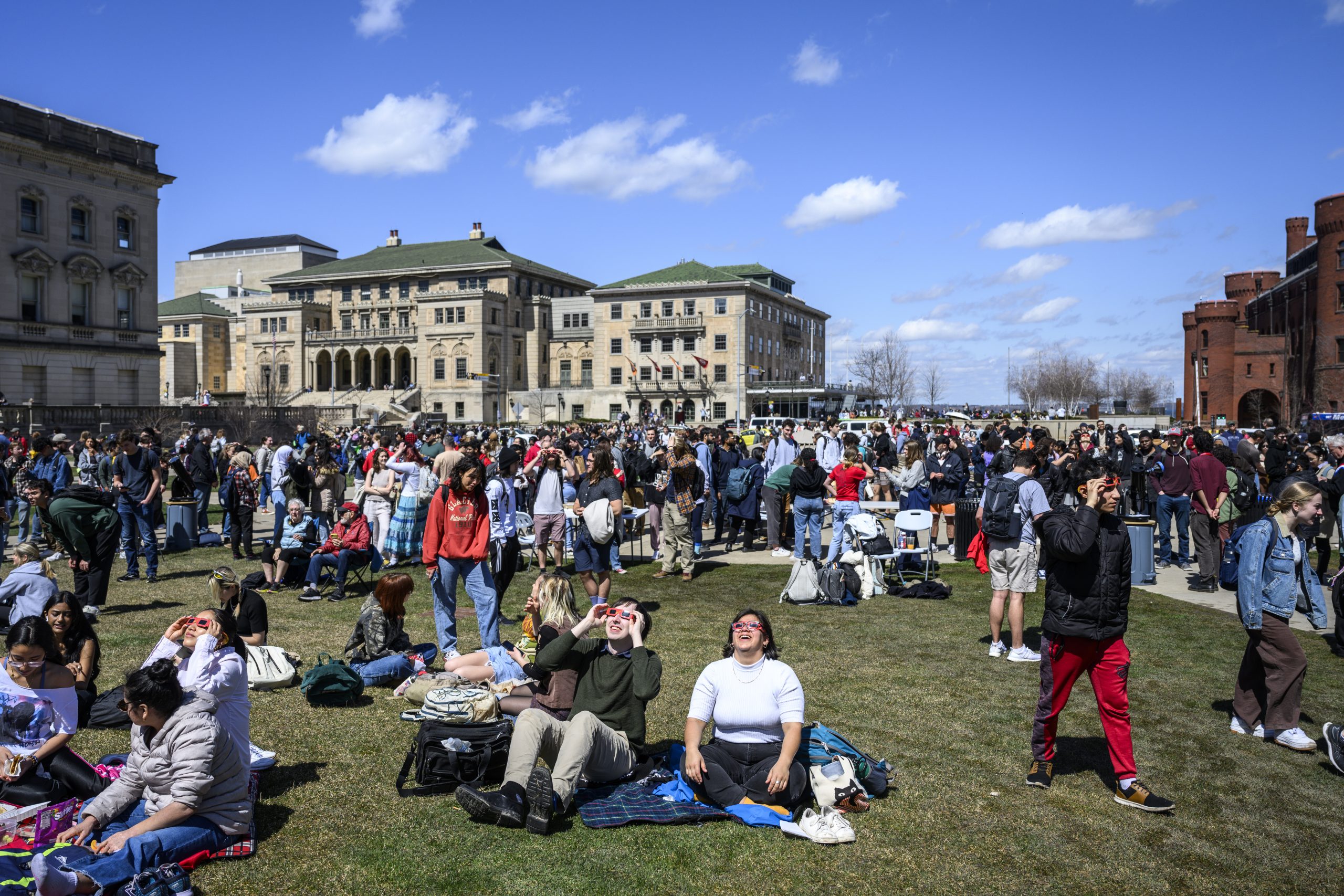 People gather on Library Mall on a spring day to view the solar eclipse.