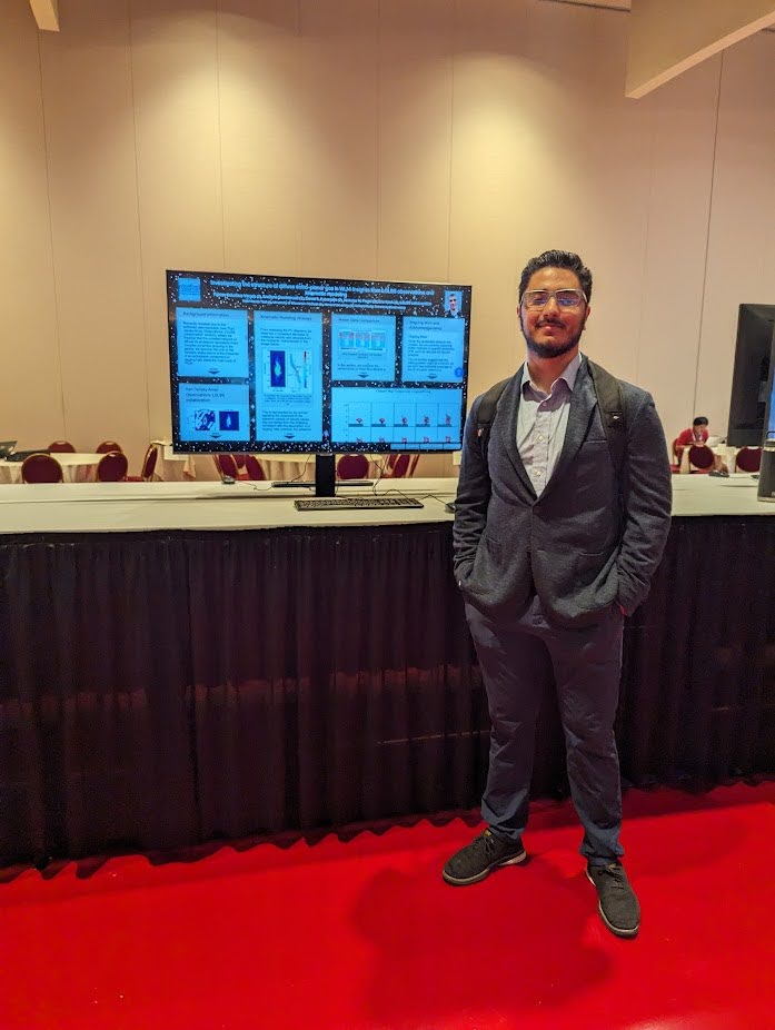 Fabian Caballero Vargas stands in front of a poster presentation, smiling with hands in pockets.