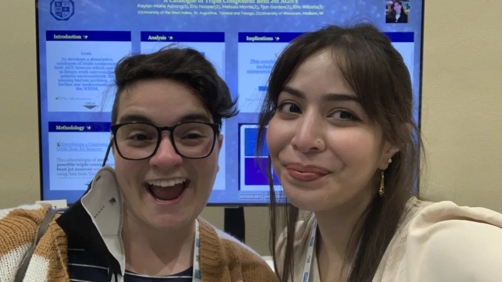 Kaylan Marie Achong and Melissa Morris smile for a selfie, in front of a poster presentation.